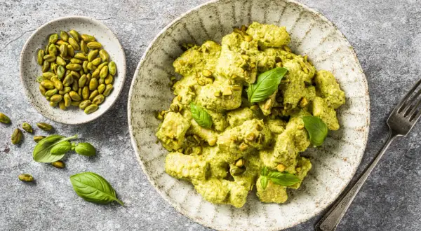 Gnocchis crémeux enrobés d'une sauce pesto onctueuse, parsemés de pistaches concassées et décorés de feuilles de basilic frais. Un délice !