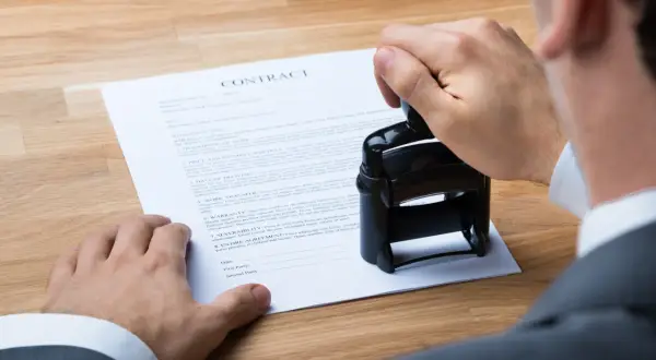 Un uomo timbra un contratto, un accordo "visto e piaciuto" che sigilla un impegno.