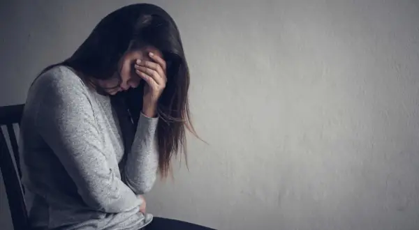 Kobieta z ręką na twarzy, pogrążona w smutku. Jak pomóc osobie z depresją która nie chce pomocy? Cierpliwość i wsparcie są kluczowe.
