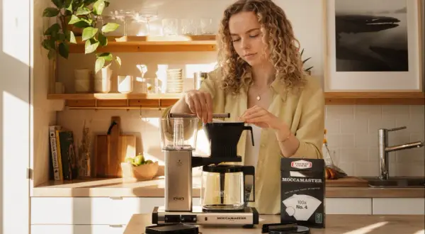 En kvinna förbereder kaffe med en Moccamaster. Hon funderar på hur mycket kaffe per liter vatten som ger bäst smak.