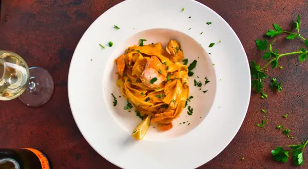 Pasta mit Lachs in cremiger Sauce, garniert mit Petersilie und Zitrone.