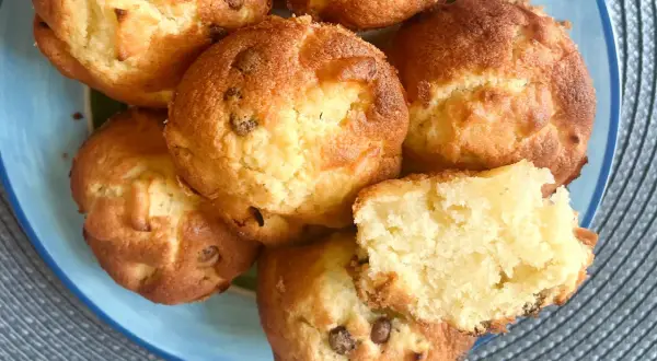 Saftige apfel muffins mit Schokoladenstückchen auf einem blauen Teller. Einer ist zerbrochen und zeigt das weiche Innere.