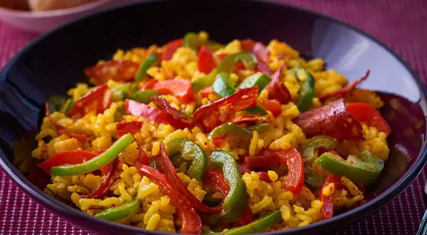Un plat appétissant de riz à l'espagnol, garni de poivrons rouges et verts, et de chorizo.