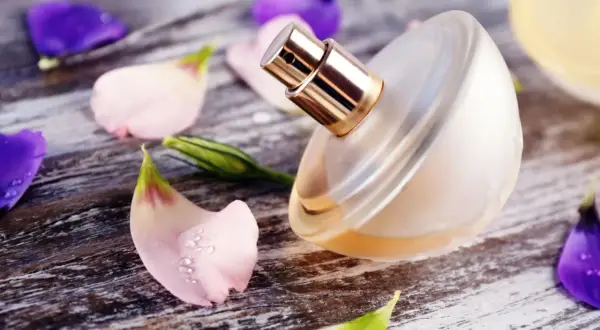 Perfumy w szklanej butelce, otoczone płatkami kwiatów. To idealny moment na refill, czyli uzupełnienie ulubionego zapachu.
