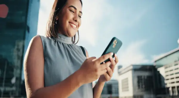 Uśmiechnięta kobieta sprawdza na telefonie, jak sprawdzić ile zostało internetu.