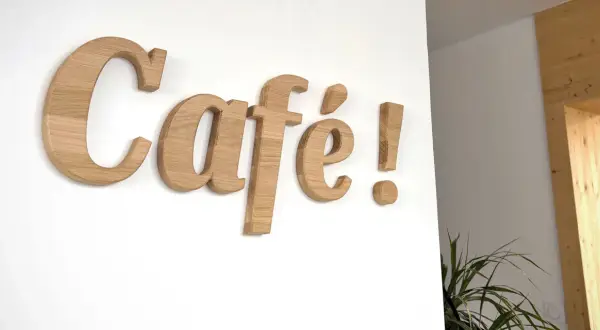 Une belle lettre en bois "Café !" orne le mur blanc, invitant à la détente.
