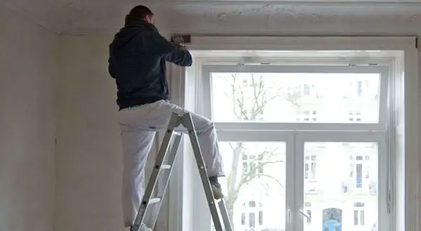 Mann auf Leiter renoviert Wohnung. Mieterrechte bei Sanierung beachten.