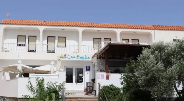 Casa Emilio Los Escullos, un hotel blanco con tejas rojas, balcón y vegetación exuberante.