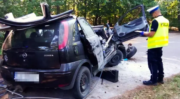 Policjant spisuje raport przy wraku Opla Corsy po wypadku. Czy to rejestracja GKS jakie miasto?