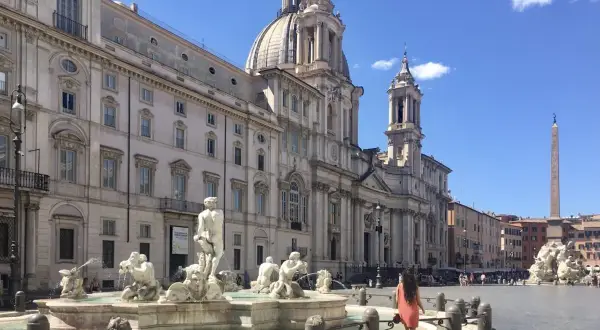 Una donna passeggia nella splendida Piazza Navona, ammirando la Fontana dei Quattro Fiumi e la maestosa chiesa.