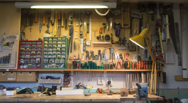 Un agencement d'atelier bricolage bien organisé, avec des outils suspendus et des tiroirs de rangement remplis.