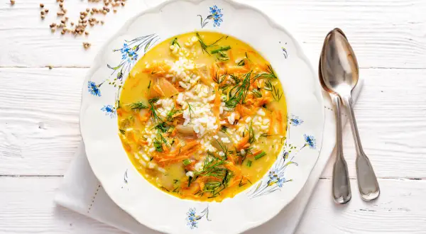 Aromaticzna zupa koperkowa z ryżem, marchewką i zielonym koperkiem, podana w ozdobnym talerzu.