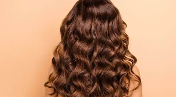 Cabello castaño largo y ondulado, con ondas definidas. Descubre cómo peinar pelo ondulado para lograr este look.