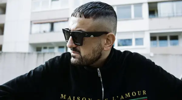 Ein Mann mit kurzgeschorenem Haar und Sonnenbrille, der die Rap-Szene repräsentiert.