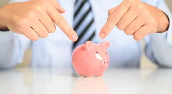 Manos señalan alcancía rosa. Es legal pedir un aval bancario para un alquiler, una garantía para tu inversión.
