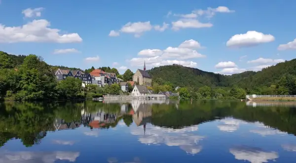 Idyllische Häuserzeile mit Kirche am Ufer des Beyenburger Stausees. Perfekt für eine entspannte Rundweg-Tour.