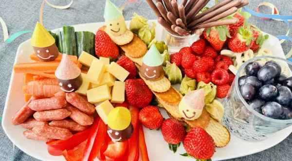 Bunter Snack-Teller mit Früchten, Käse, Würstchen und lustigen Figuren mit Partyhüten – perfekt für Fasching im Kindergarten!
