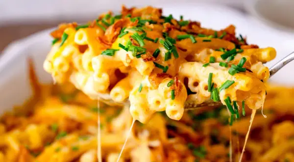Cremiges Mac and Cheese mit knusprigen Zwiebeln und frischem Schnittlauch, das Käse zieht. Ein Genuss!