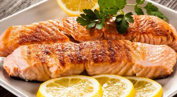 Filetti di salmone succulenti, cotti alla perfezione, con fette di limone e prezzemolo. Un piatto che fa pensare al salmone in gravidanza, ricco di omega-3.