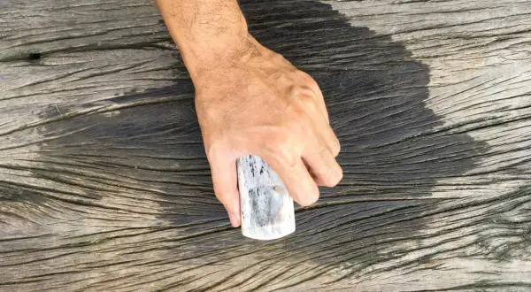 Hand håller en bit trä för att rengöra trallrent eller såpa.
