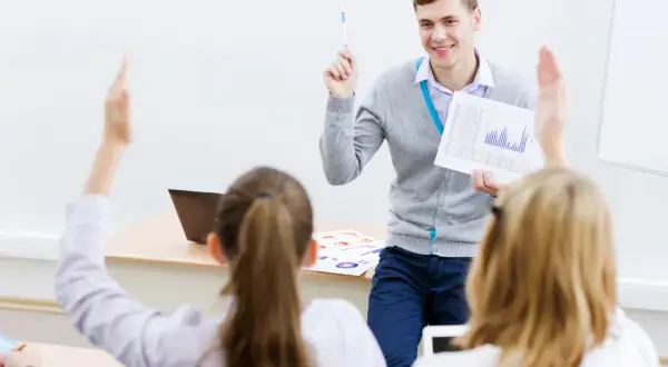 Lehrer erklärt den Unterschied zwischen dualem und berufsbegleitendem Studium. Schüler melden sich.