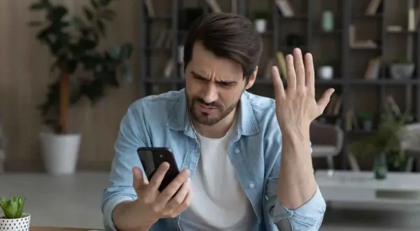 Mężczyzna zmartwiony przegrzewaniem się telefonu. Dba o bezpieczną temperaturę urządzenia, by uniknąć uszkodzeń.