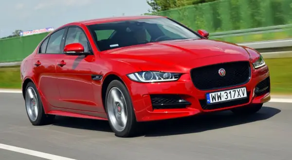 Czerwony Jaguar XE w ruchu na drodze.