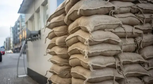 Stos worków cementu na palecie, gotowy do budowy. Widać ich wiele, trudno policzyć ile worków cementu na palecie.