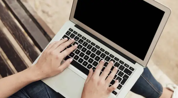 Dłonie na klawiaturze laptopa. Dowiedz się, jak zrobić screena na laptopie, by uwiecznić ważne momenty.