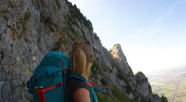 Wanderin auf dem Salzburger Hochthron, mit Blick auf steile Felsen und das Tal.