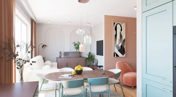 Otwarty salon z jadalnią i kuchnią. Jasne wnętrze z pastelowymi akcentami, wygodna sofa, stół z krzesłami i nowoczesna zabudowa kuchenna.
