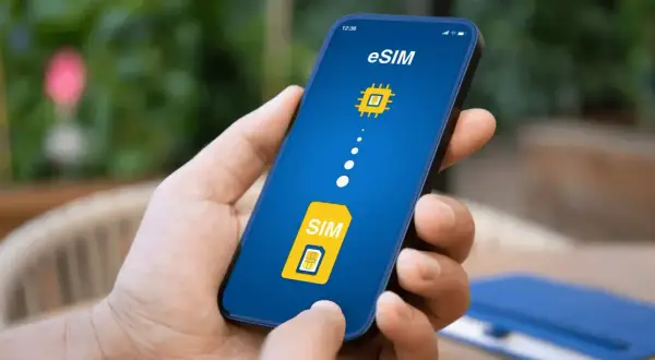 Dłoń trzyma smartfon z ekranem pokazującym ikonę karty SIM i symbol chipa, symbolizujące kartę eSIM.