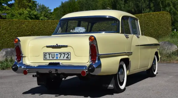 En ljusgul Vauxhall Victor från 1950-talet, en klassisk modell, står parkerad utomhus.
