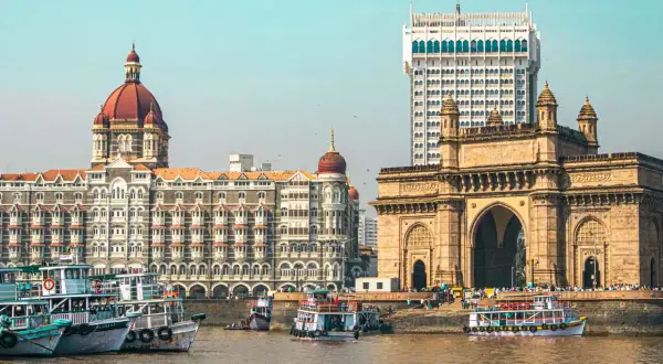 Brama Indii i hotel Taj Mahal Palace w Mumbaju, Indie. Wokół pływają łodzie.