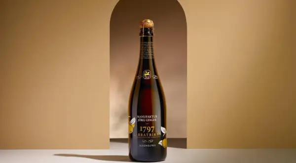 Eine Flasche "1797 C-Bratbirne" von Manufaktur Jörg Geiger, eine edle Champagner Alternative, steht im Scheinwerferlicht.