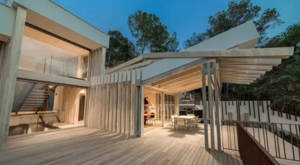 Terraza moderna con suelo de madera Accoya, pérgola y fachada acristalada.
