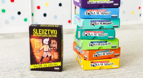 Stos kolorowych pudełek z grami edukacyjnymi "Bojka na słówka" i "Śledztwo". Gry typu państwa miasta, nauka języków i tabliczki mnożenia.