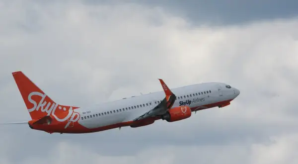 Samolot SkyUp Airlines wznosi się na tle pochmurnego nieba.