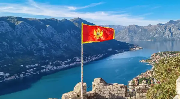 Czarnogóra, z flagą na tle gór i zatoki, nie jest w UE.