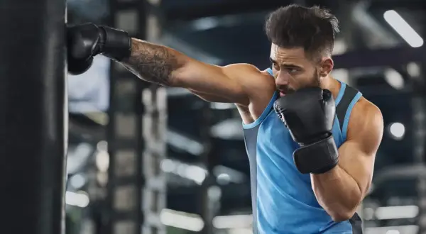 A boxer trains intensely, punching a heavy bag. This workout is a great way to see how many calories does boxing burn, boosting fitness and strength.