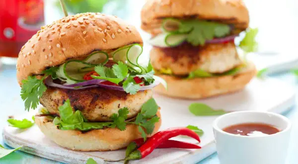 Deliciosa hamburguesa de pollo con pepino, cebolla morada, cilantro y chile rojo. ¡Un festín para los sentidos!