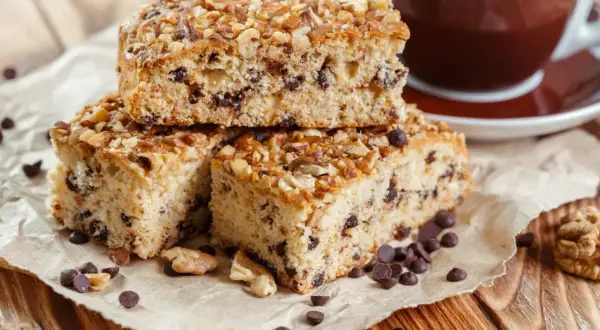 Fette di ciambellone marchigiano ricetta originale, con gocce di cioccolato e noci, accanto a una tazza di caffè.
