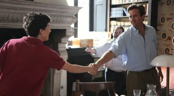 Elio und Oliver schütteln sich die Hände, ein Moment, der an "Call Me By Your Name 2" erinnert. Ein Mann im Hintergrund lächelt.