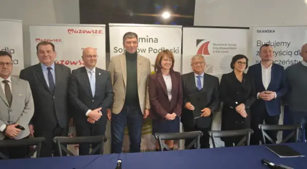 Grupa osób pozuje do zdjęcia na tle banerów informujących o budowie obwodnicy Sokołowa Podlaskiego.