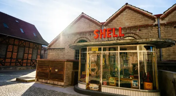 Retro Shell-Tankstelle im Motorworld Metzingen, mit Fachwerkhaus im Hintergrund.