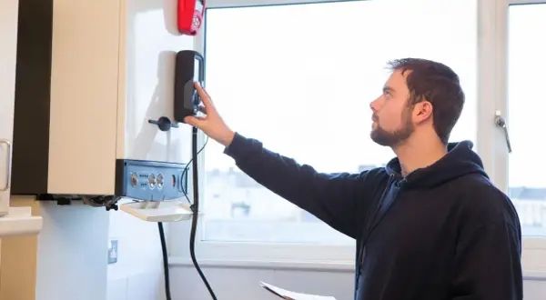 Un technicien ajuste la commande d'une chaudière à condensation.
