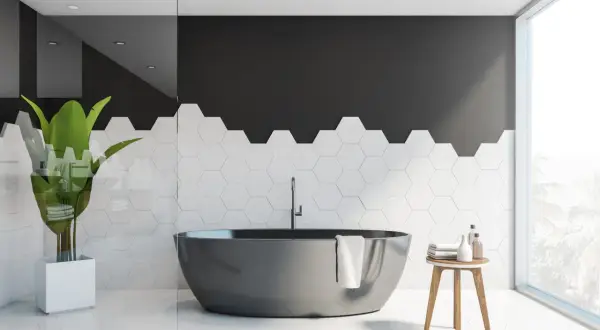Bagno moderno con vasca scura e piastrelle esagonali bianche. Idee per dipingere piastrelle bagno: contrasto tra nero e bianco.