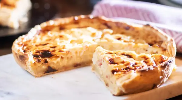 Ein köstliches Quiche Rezept, goldbraun gebacken, mit einem Stück zum Probieren.