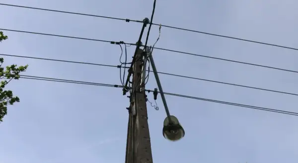Słup energetyczny z wiszącą lampą uliczną, gdzie mogło dojść do kradzieży prądu. Policja bada sprawę.