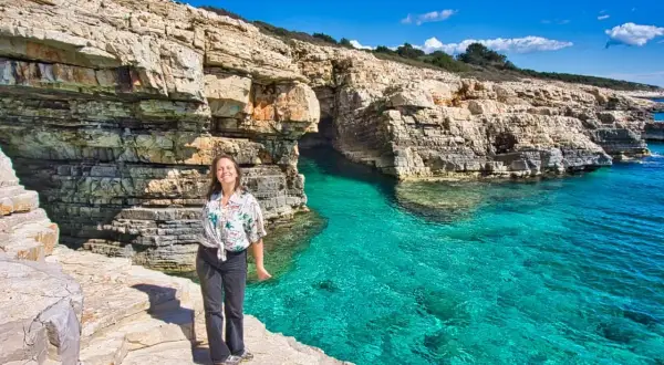 Frau genießt die Sonne an einer felsigen Küste mit türkisfarbenem Wasser. Perfekte pula unternehmungen für einen Urlaub.